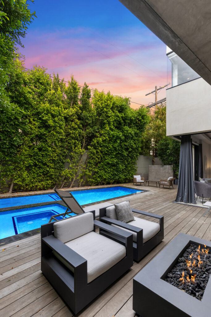 Modern pool deck with a fire pit and outdoor seating at dusk in Beverly Grove.