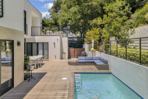 `Heated pool and outdoor living area surrounded by lush gardens at Lexington Villa Beverly Hills`