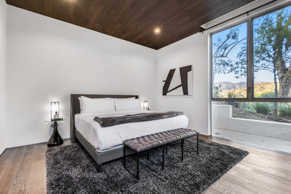 Well-appointed guest bedroom featuring a calm modern palette and wood floors.