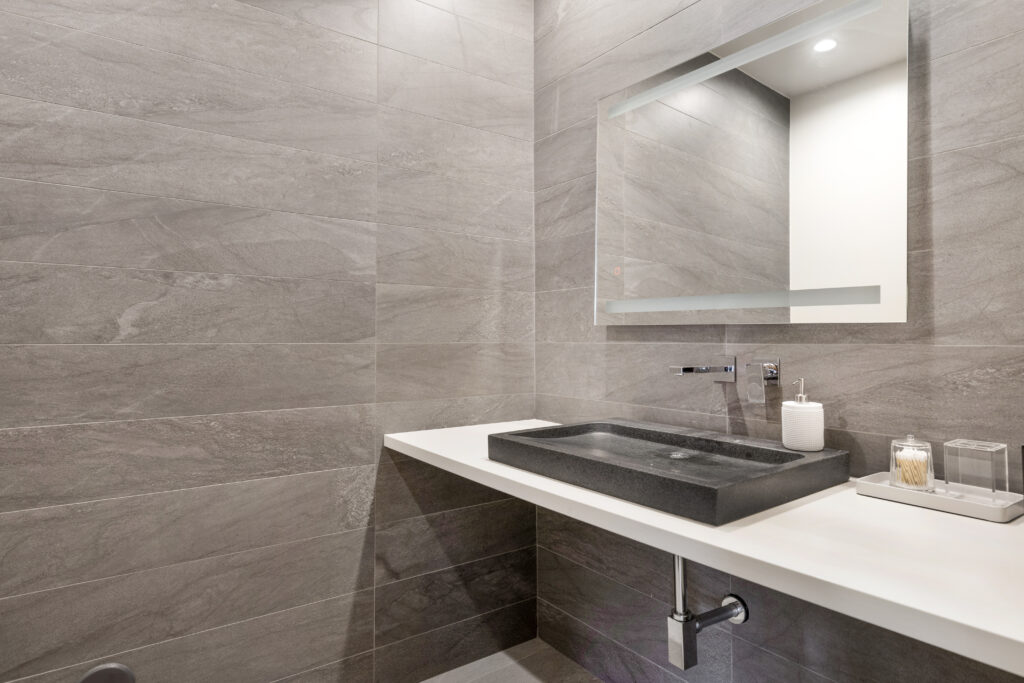 Sleek guest powder room with minimalist grey stone tiling and modern sink.