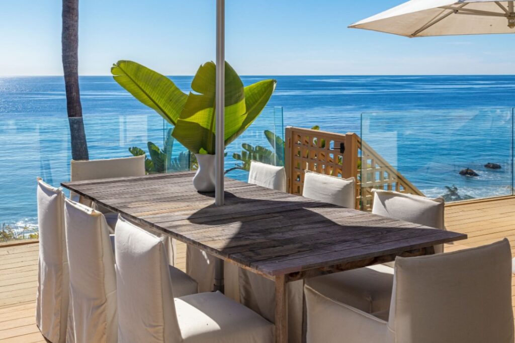 Patio dining area framed by lush greenery and ocean views