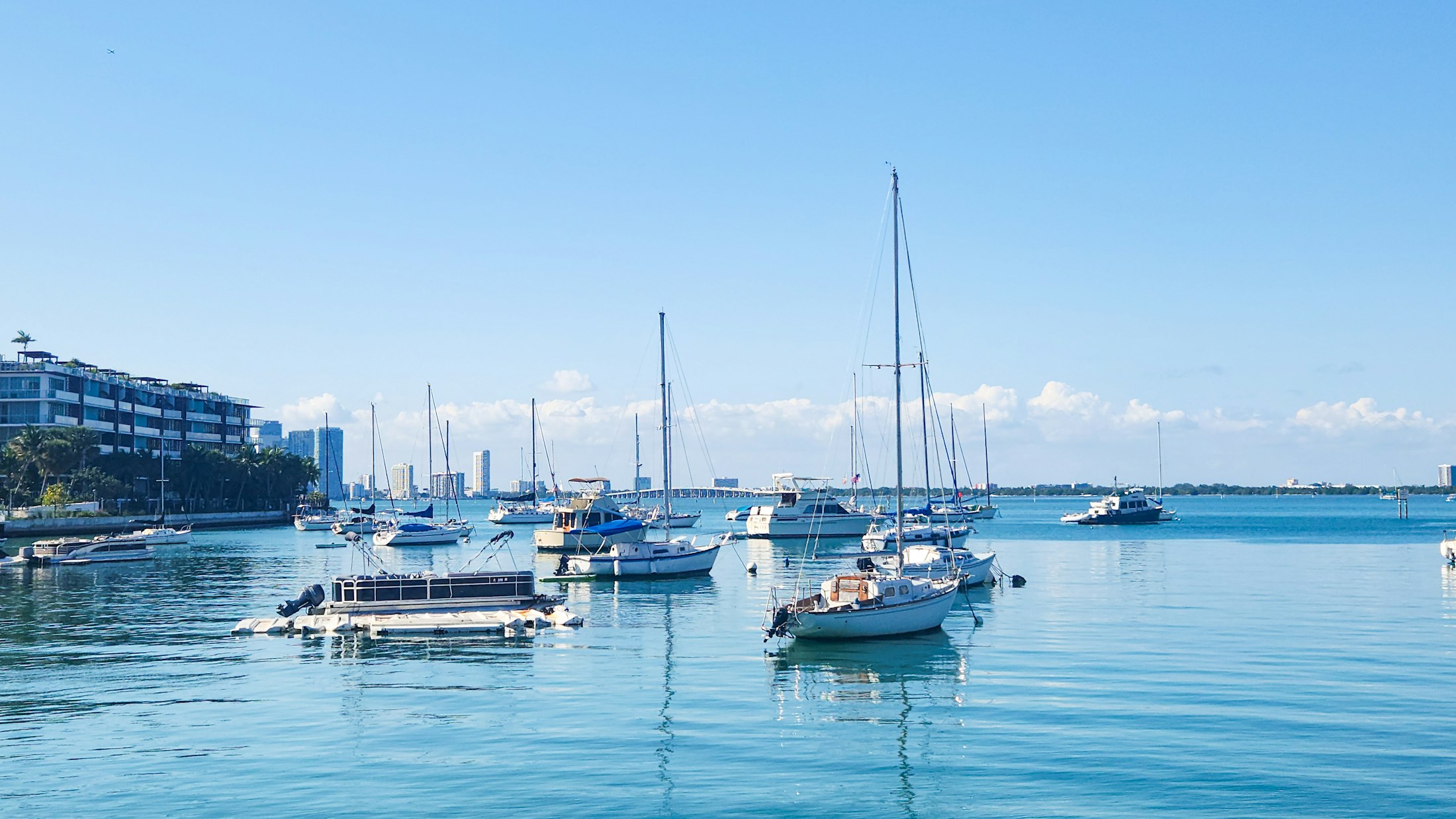 Sailboats and yachts at anchor on Biscayne Bay, Miami, under a clear sky