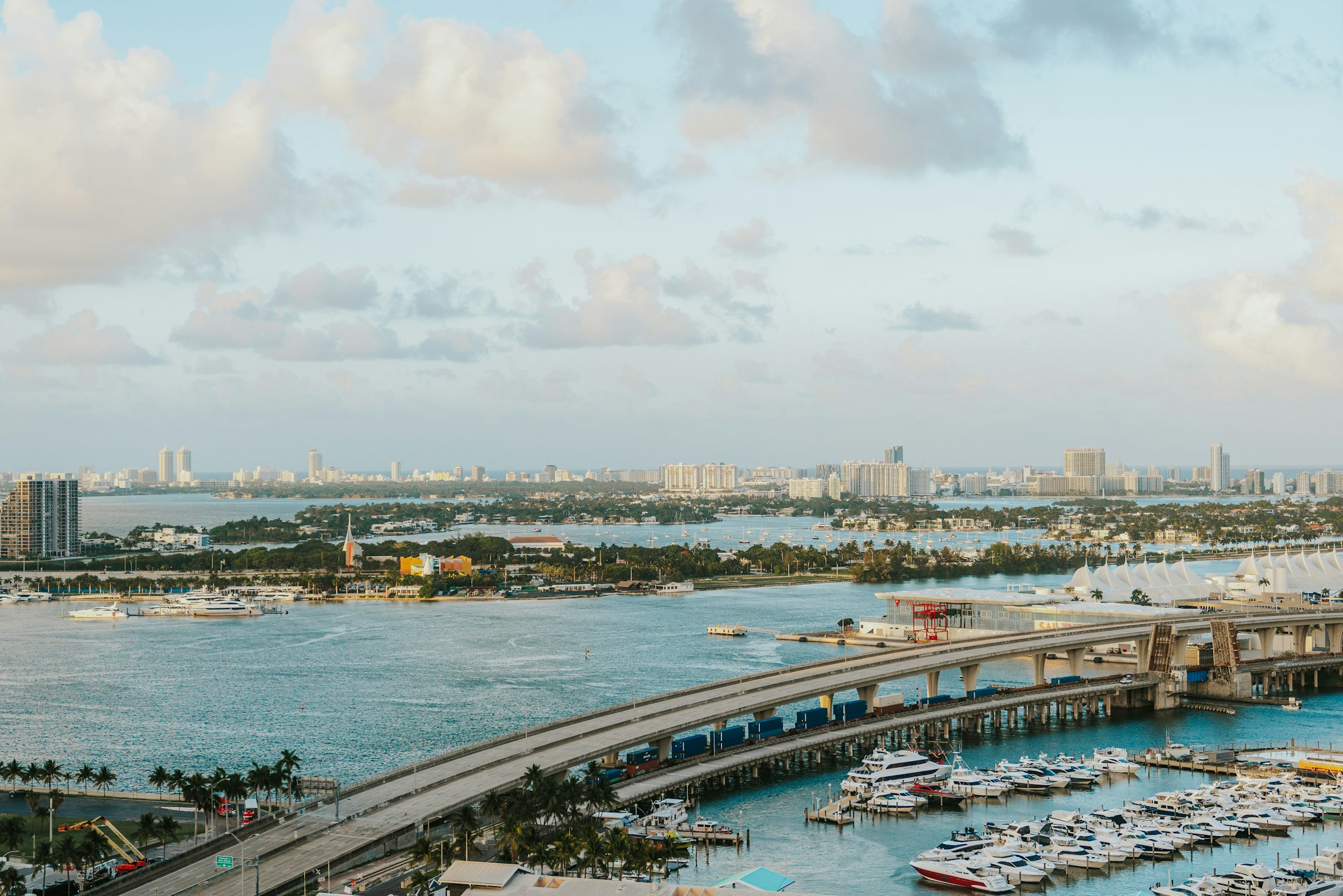 Aerial view of a Miami harbor with yachts and a causeway bridge